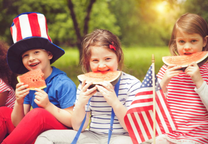 Children enjoying fresh watermelon during an outdoor Fourth of July picnic celebration