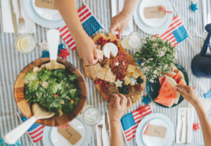 Healthy July 4th cookout spread featuring fresh salad, fruit, charcuterie board, and nutritious holiday foods
