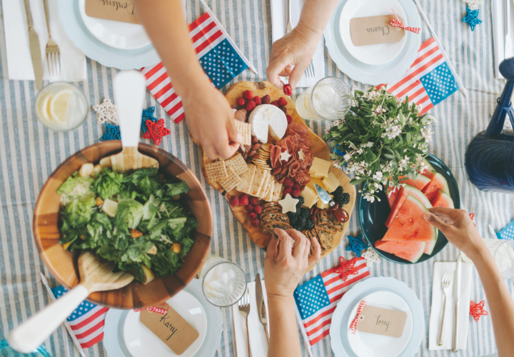 Healthy July 4th cookout spread featuring fresh salad, fruit, charcuterie board, and nutritious holiday foods