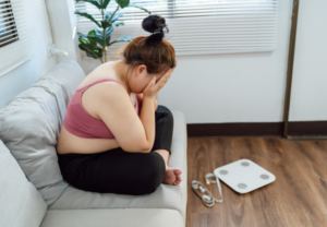Woman feeling frustrated after stepping on a scale while struggling with weight gain during antidepressant treatment.