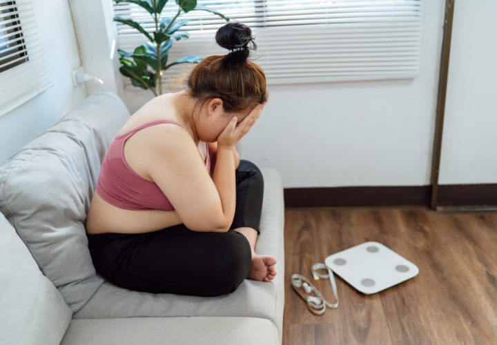 Woman feeling frustrated after stepping on a scale while struggling with weight gain during antidepressant treatment.