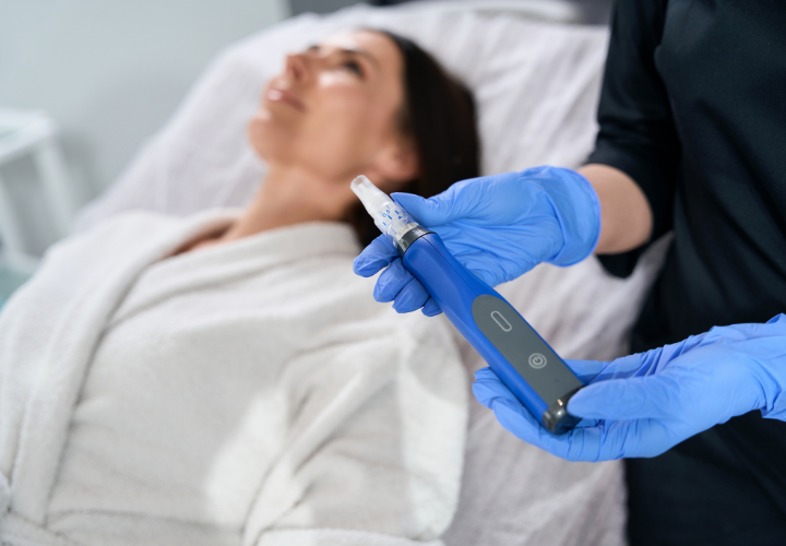 Provider preparing a microneedling device for a woman receiving a facial skin rejuvenation treatment
