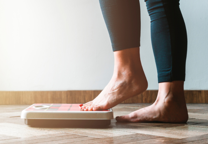 Person standing on a bathroom scale while tracking body weight