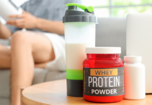 Scoop of protein powder next to a protein supplement container