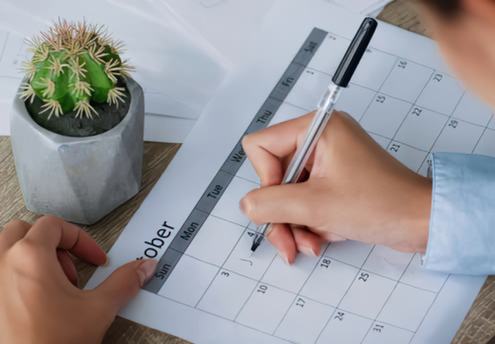 Person marking a monthly calendar to track a 30-day healthy habit goal