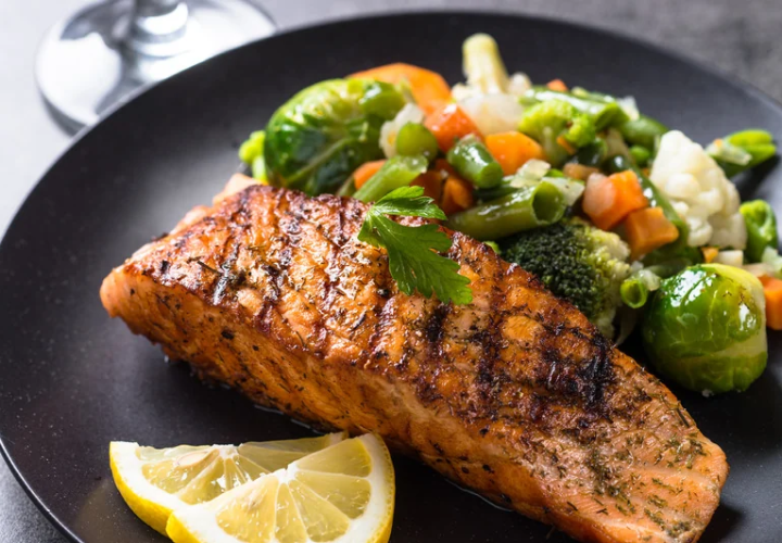 Grilled salmon with mixed vegetables and lemon, illustrating nutritious foods that support joint health.