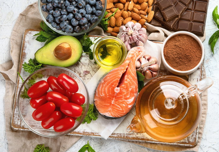 Salmon, blueberries, avocado, almonds, olive oil, and tomatoes arranged with other nutrient-rich foods.